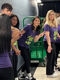 a group of girls in purple shirts standing in a hallway